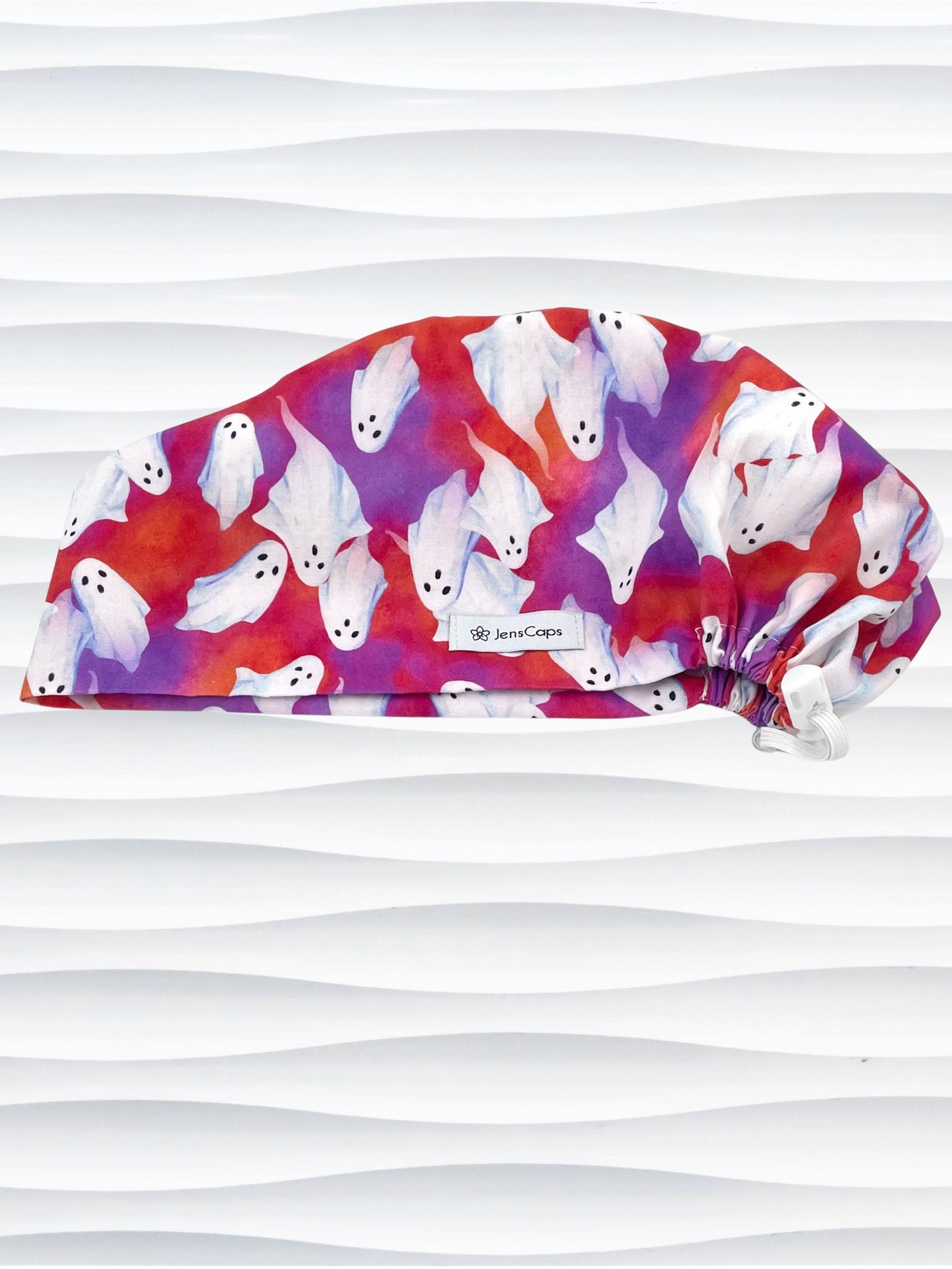 Euro Pixie style surgical scrub cap by JensCaps with white sheet ghosts tossed all aver an ombre red and purple cotton fabric.