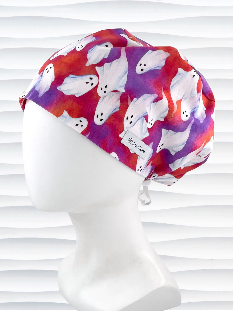 Euro Pixie style surgical scrub cap by JensCaps with white sheet ghosts tossed all aver an ombre red and purple cotton fabric.