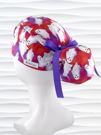 Ponytail style surgical scrub cap by JensCaps with white sheet ghosts tossed all aver an ombre red and purple cotton fabric.