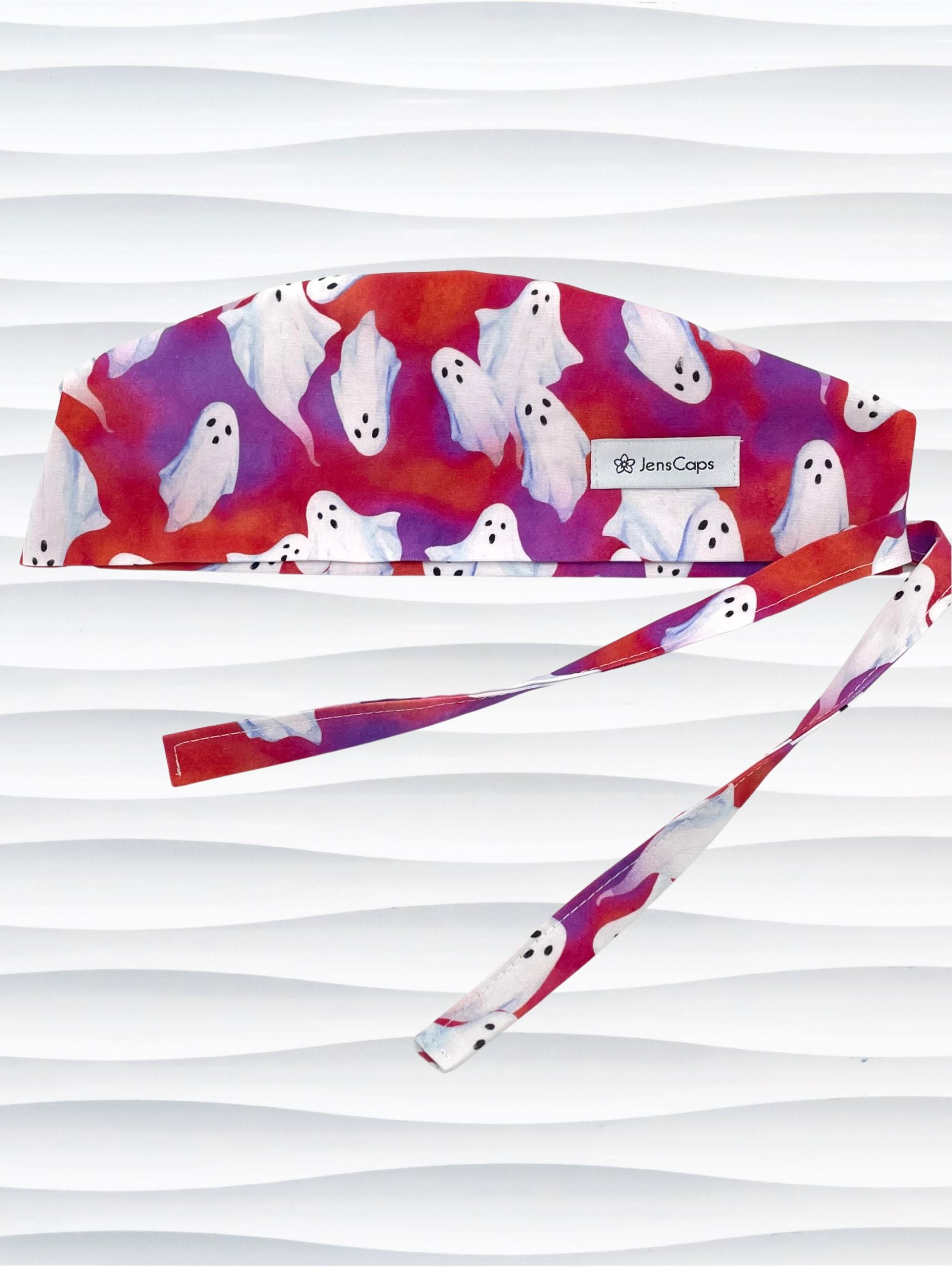 Surgeon style surgical scrub cap by JensCaps with white sheet ghosts tossed all aver an ombre red and purple cotton fabric.