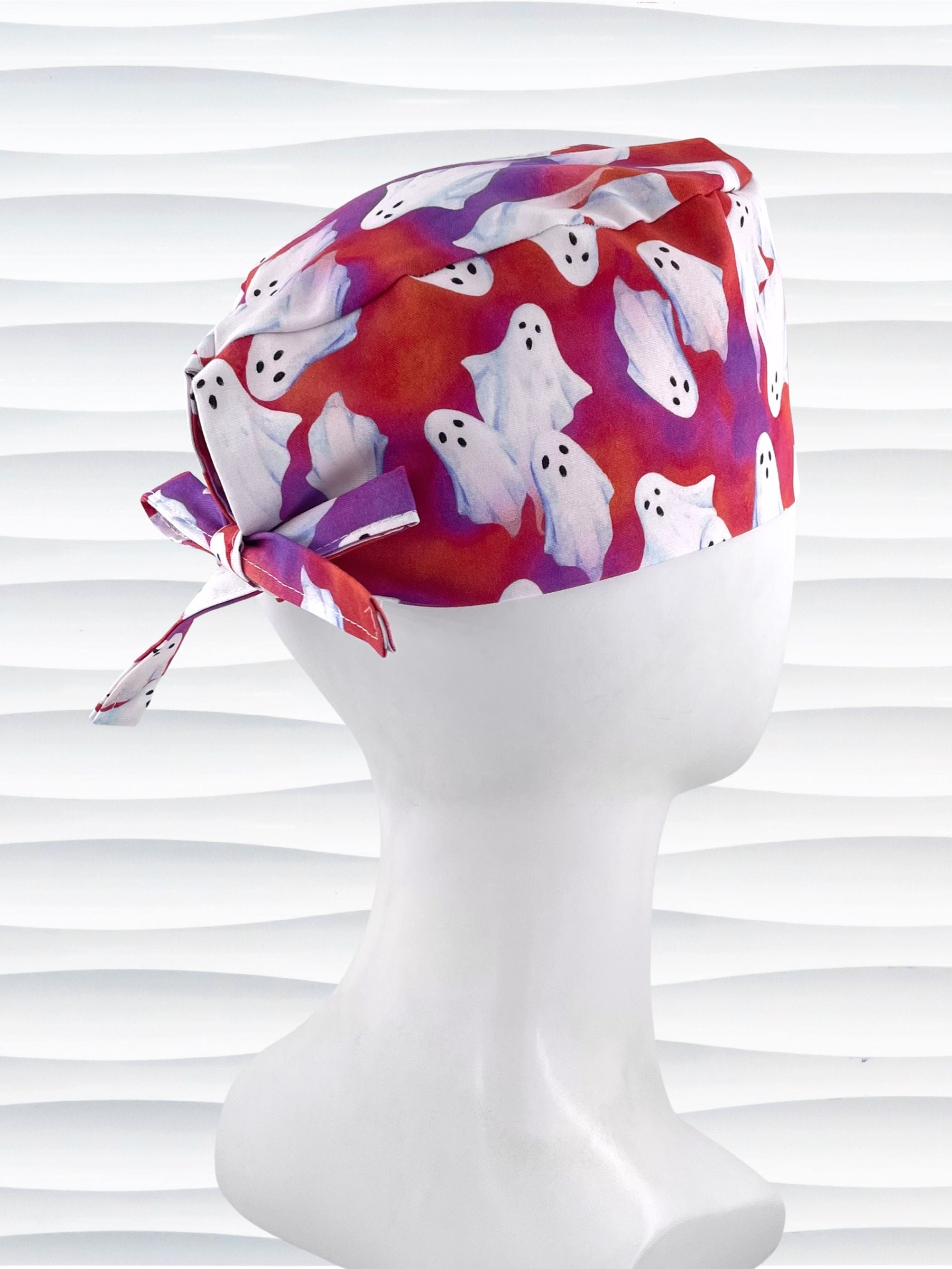 Surgeon style surgical scrub cap by JensCaps with white sheet ghosts tossed all aver an ombre red and purple cotton fabric.