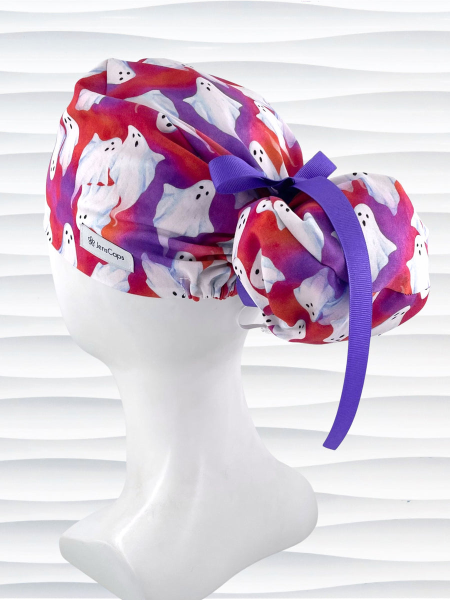 Euro Pony ponytail style surgical scrub cap by JensCaps with white sheet ghosts tossed all aver an ombre red and purple cotton fabric.