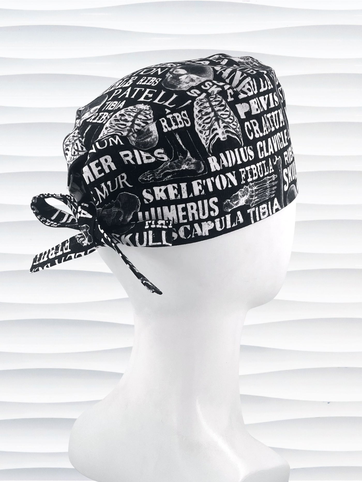 Anatomy-themed surgical scrub cap for medical professionals, featuring detailed white illustrations of the human skeleton with labeled bones like skull, mandible, and tibia on a black background