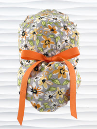Ponytail style surgical scrub cap by JensCaps with yellow, white, and black flowers on a gray cotton fabric, finished with a grosgrain ribbon, and displayed on a mannequin head.