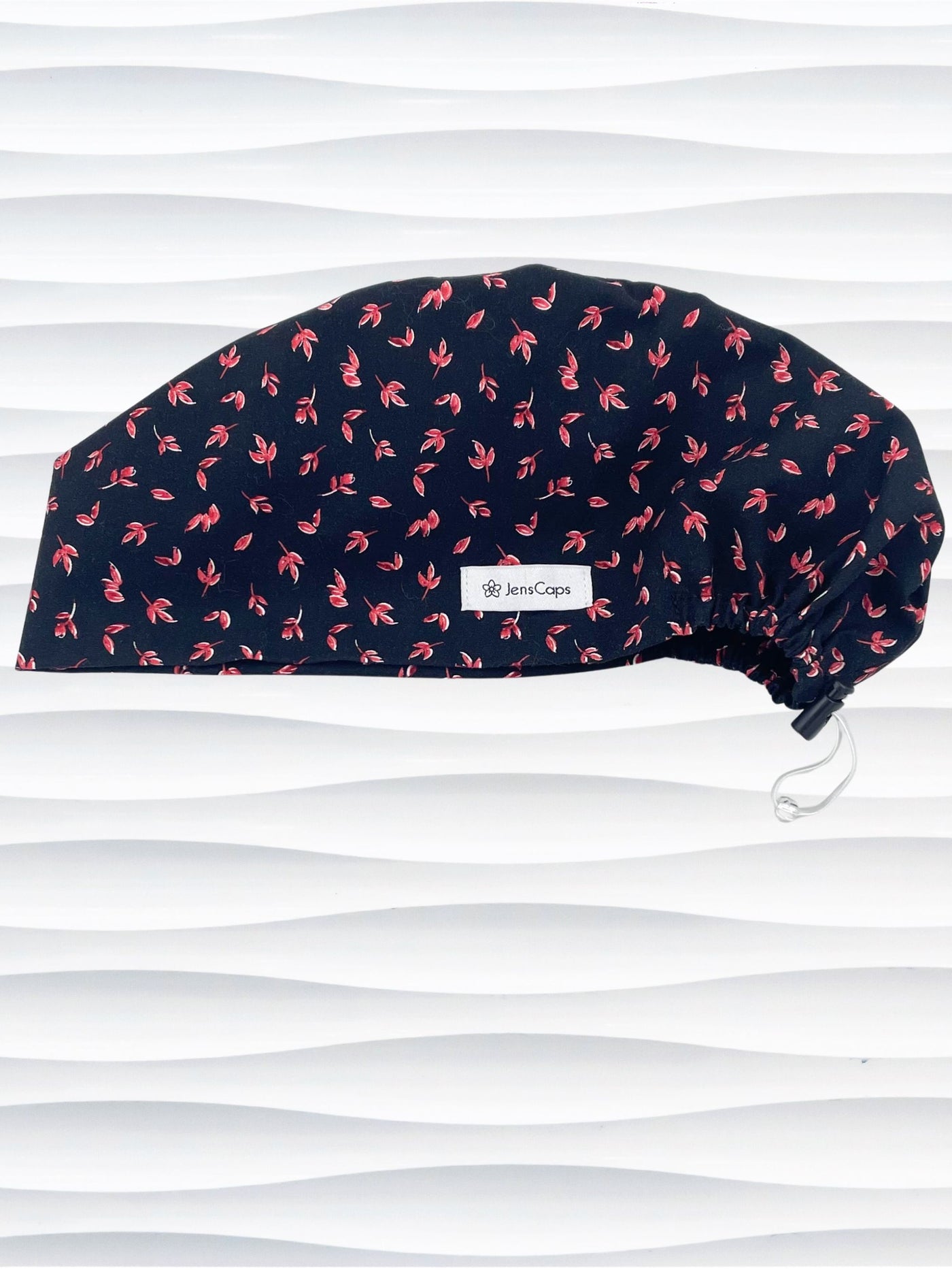 Black scrub cap with pink floral pattern on a mannequin head against a white background