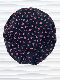 Black scrub cap with pink floral pattern on a mannequin head against a white background