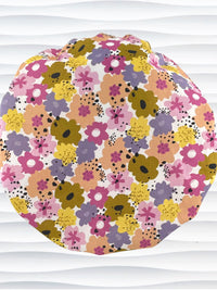 Bouffant style surgical scrub cap by JensCaps with pink, purple, yellow, and green flowers all over white cotton fabric  and displayed on a mannequin head.