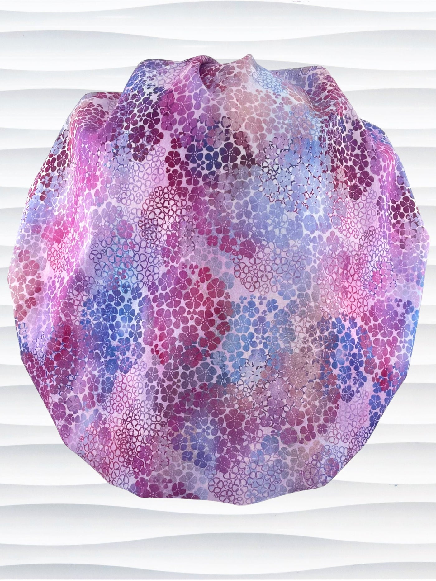 Bouffant style surgical scrub cap by JensCaps with small daisies in pink, blue, and purple all over cotton fabric and displayed on a mannequin head