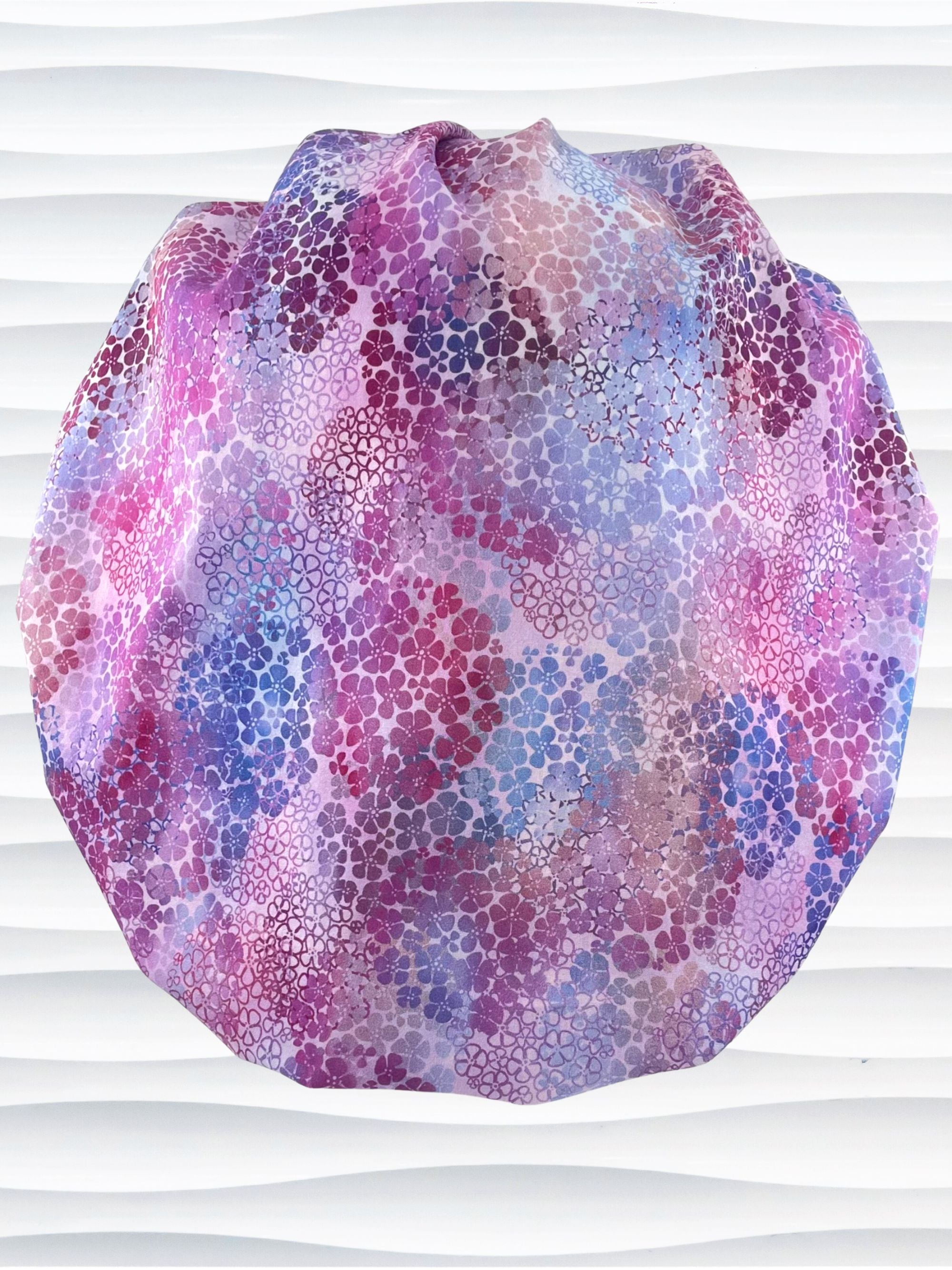 Bouffant style surgical scrub cap by JensCaps with small daisies in pink, blue, and purple all over cotton fabric and displayed on a mannequin head