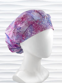 Bouffant style surgical scrub cap by JensCaps with small daisies in pink, blue, and purple all over cotton fabric and displayed on a mannequin head