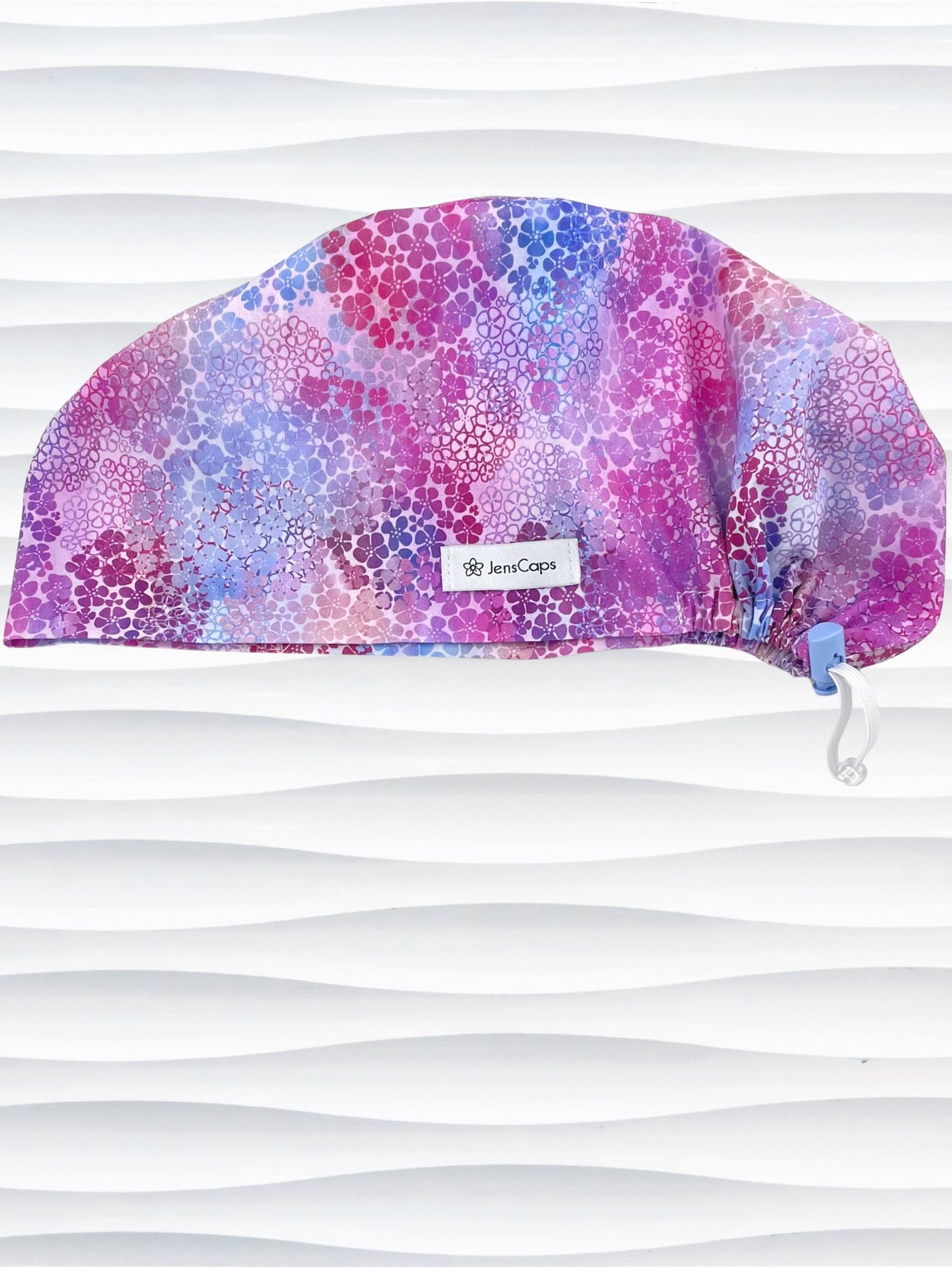 style surgical scrub cap by JensCaps with small daisies in pink, blue, and purple all over cotton fabric and displayed on a mannequin head