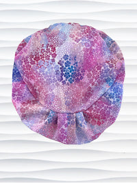 style surgical scrub cap by JensCaps with small daisies in pink, blue, and purple all over cotton fabric and displayed on a mannequin head
