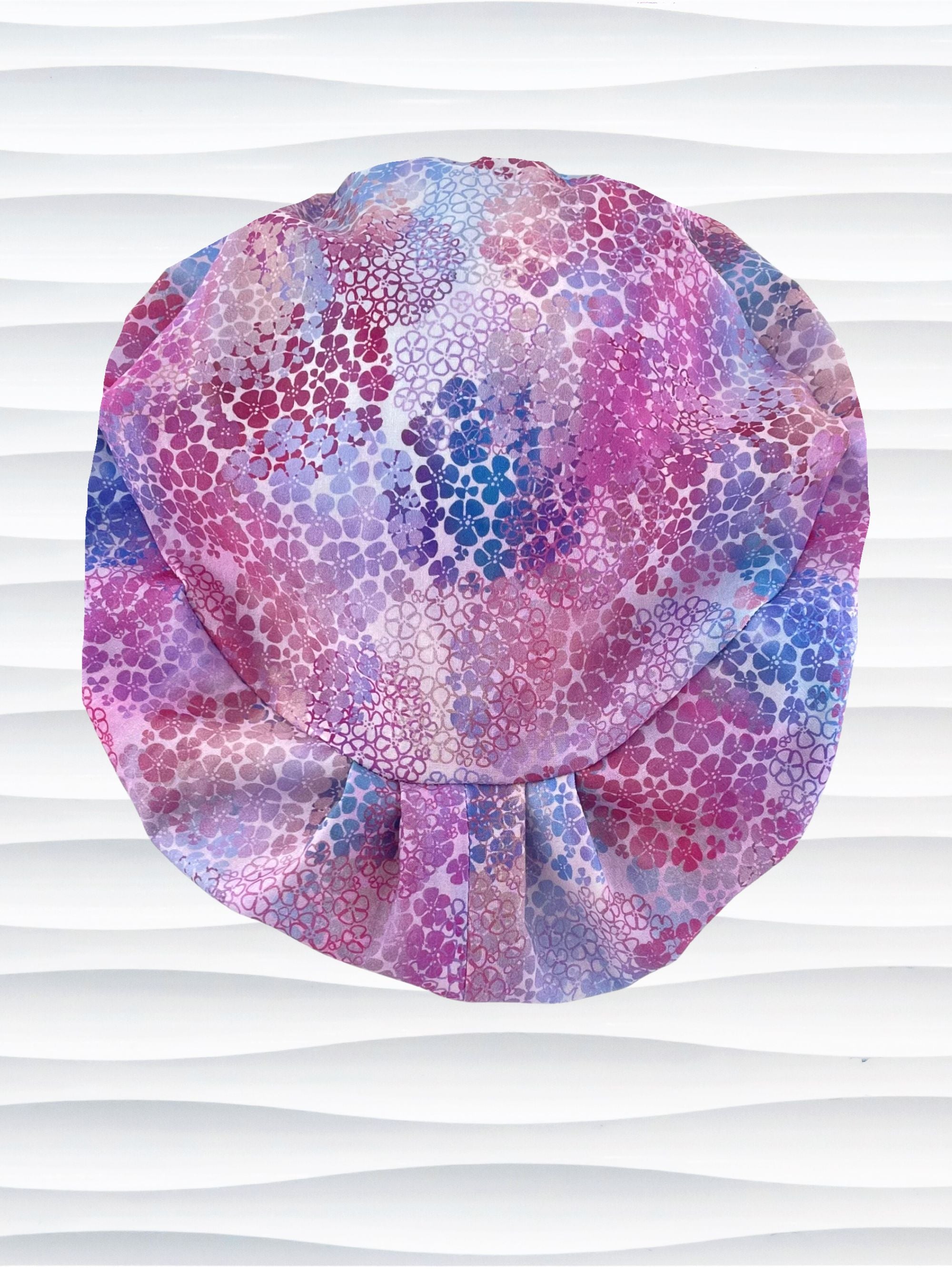 style surgical scrub cap by JensCaps with small daisies in pink, blue, and purple all over cotton fabric and displayed on a mannequin head