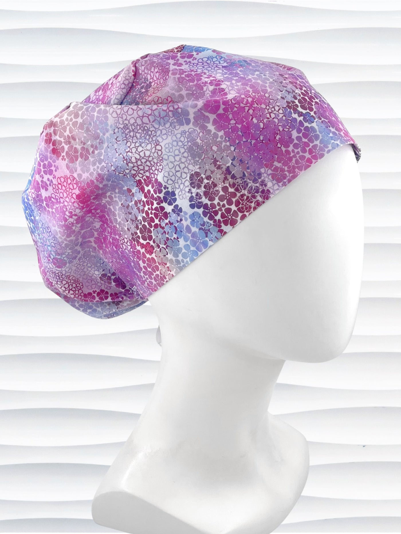 style surgical scrub cap by JensCaps with small daisies in pink, blue, and purple all over cotton fabric and displayed on a mannequin head