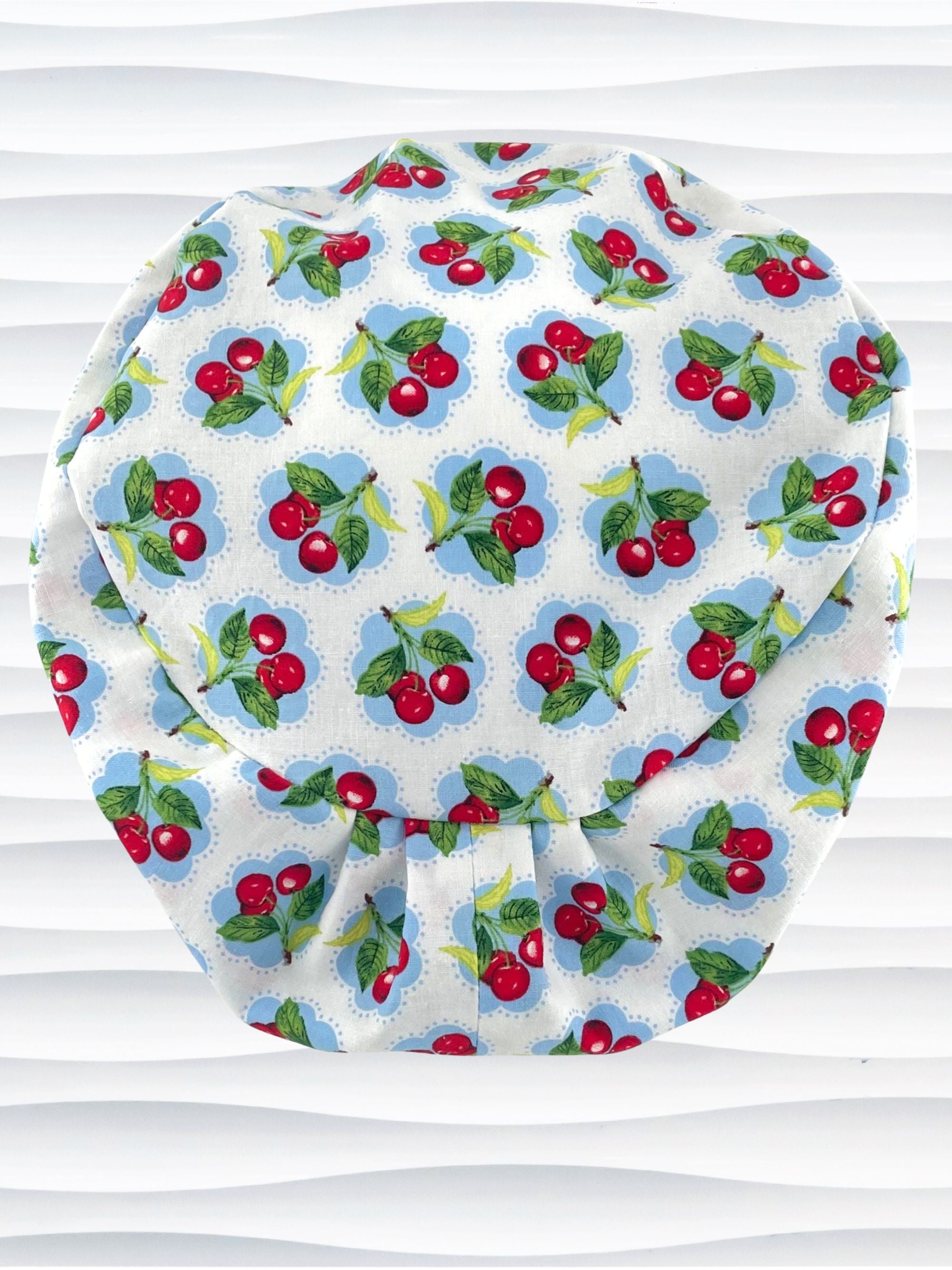 Euro Pixie style surgical scrub cap by JensCaps with red cherries blue polka dots on white cotton fabric and diplayed on a mannequin head.