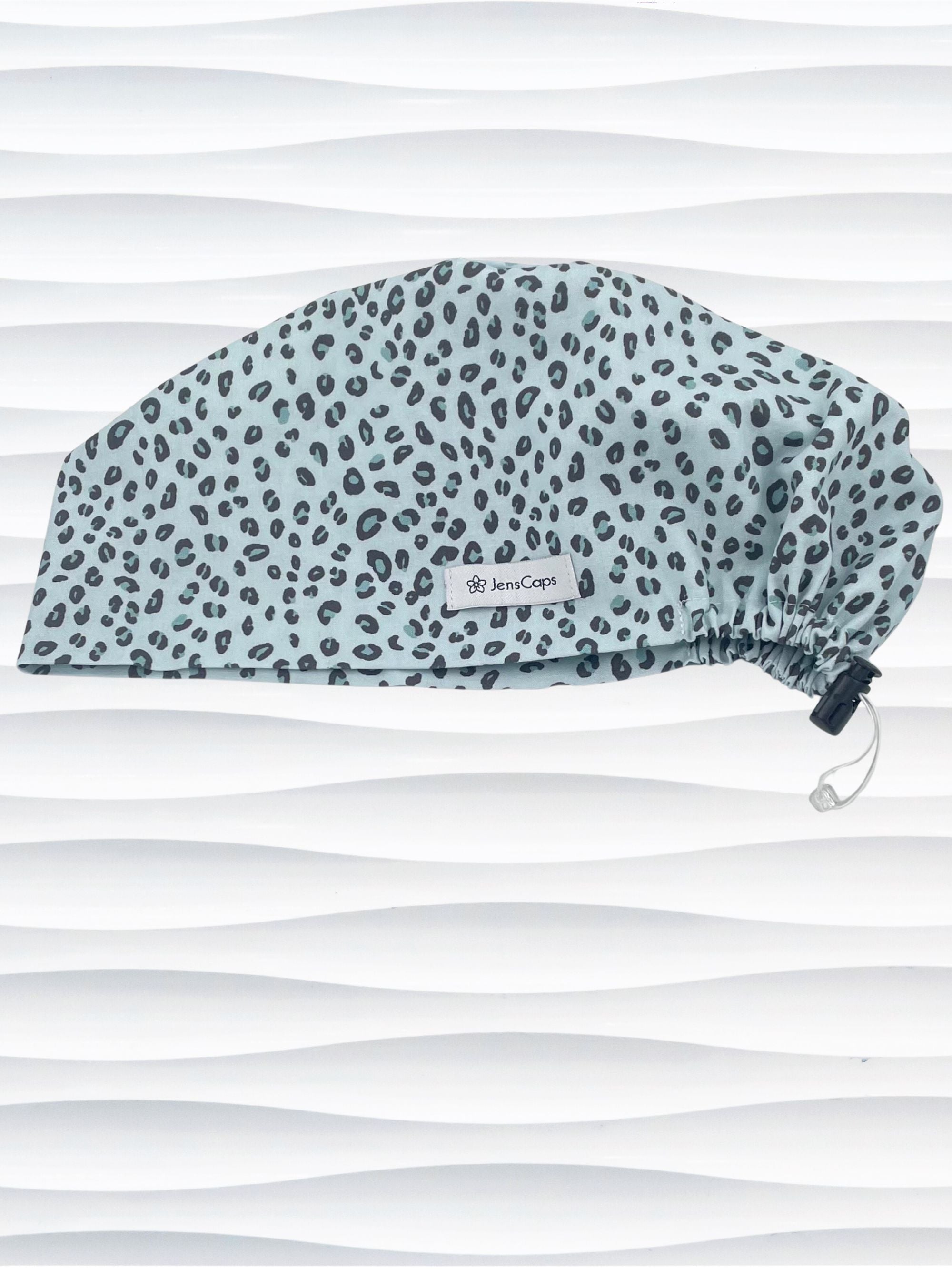 Euro Pixie style surgical scrub cap by JensCaps with a leopard print on light teal cotton fabric and displayed on a mannequin head.