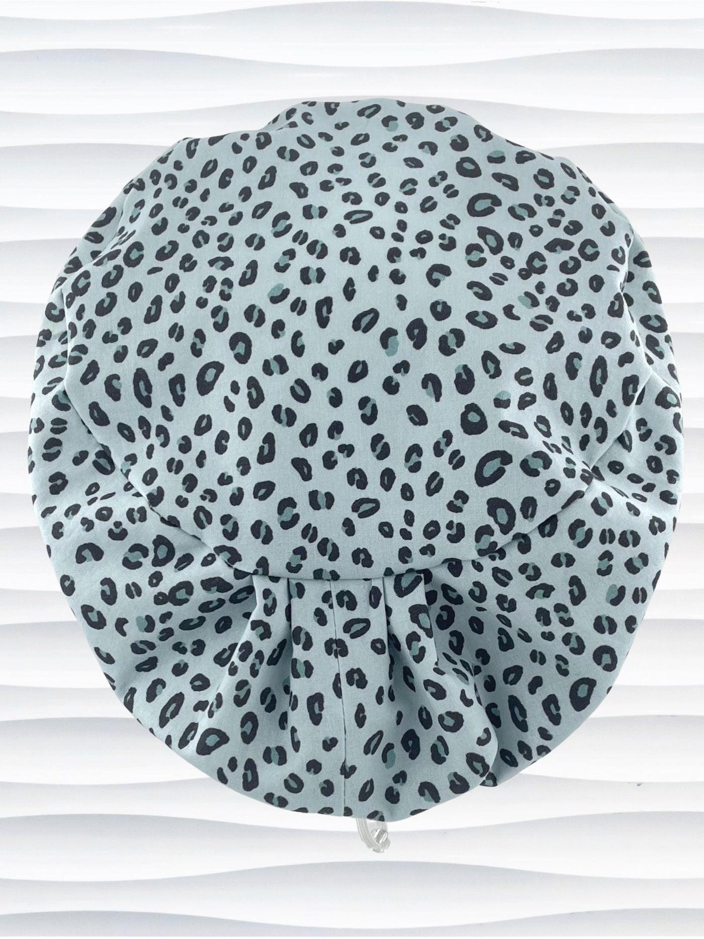 Euro Pixie style surgical scrub cap by JensCaps with a leopard print on light teal cotton fabric and displayed on a mannequin head.