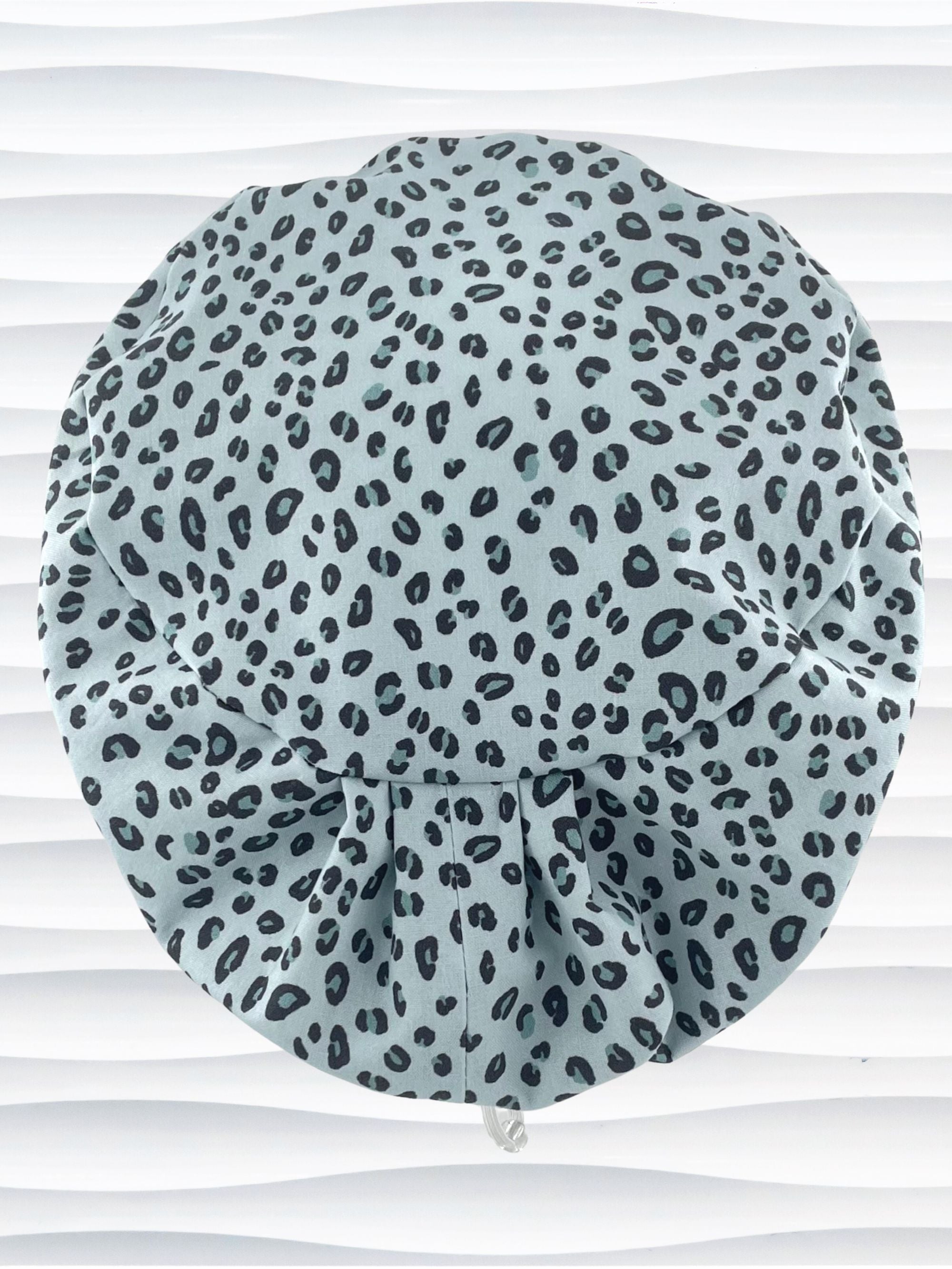 Euro Pixie style surgical scrub cap by JensCaps with a leopard print on light teal cotton fabric and displayed on a mannequin head.