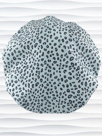 Bouffant style surgical scrub cap by JensCaps with a leopard print on light teal cotton fabric, and displayed on a mannequin head.