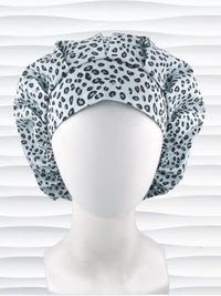 Bouffant style surgical scrub cap by JensCaps with a leopard print on light teal cotton fabric, and displayed on a mannequin head.