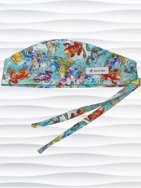 Surgical scrub cap by JensCaps in an adjustable tie-back style with a colorful watercolor frog print in orange, purple, green, and blue on an aqua background