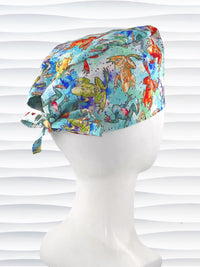 Surgical scrub cap by JensCaps in an adjustable tie-back style with a colorful watercolor frog print in orange, purple, green, and blue on an aqua background and displayed on a mannequin head 