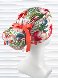 Euro Pony style surgical scrub cap by JensCaps with tropical hibiscus flowers and palm fronds all over white cotton fabric, finished with a grosgrain ribbon tie, and displayed on a mannequin head