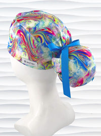 Ponytail style surgical scrub cap by JensCaps with an abstract marbled swirl print in blue, pink, yellow, and green, finished with a grosgrain ribbon, and displayed on a white mannequin head.