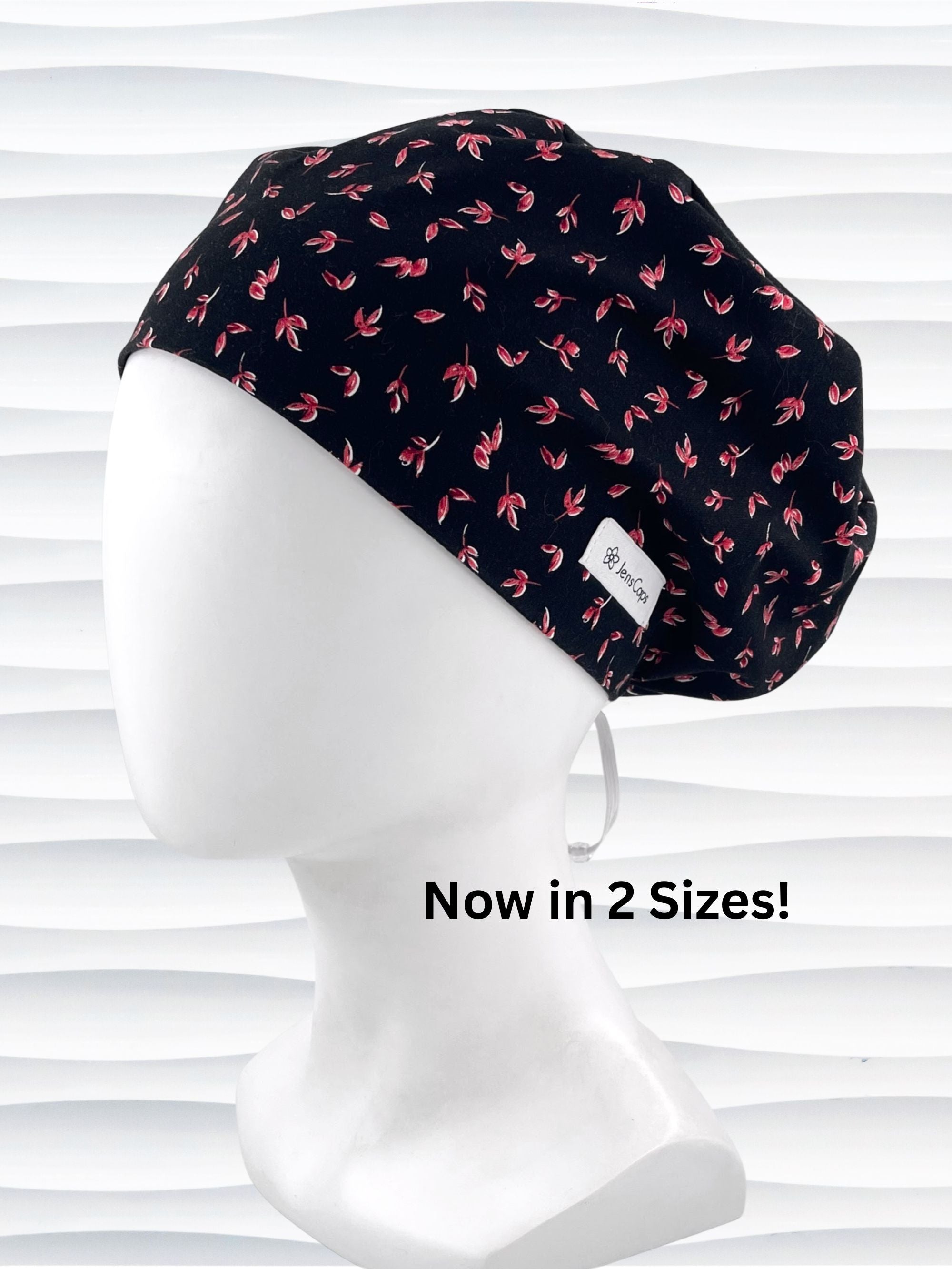 Black scrub cap with pink floral pattern on a mannequin head against a white background.