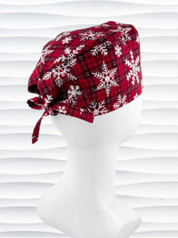 Red and white plaid scrub cap with snowflakes on a mannequin head against a white background.