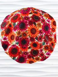 Bouffant surgical scrub cap by JensCaps with fall colored sunflowers in pinks, orange, and reds on a white background cotton fabric.