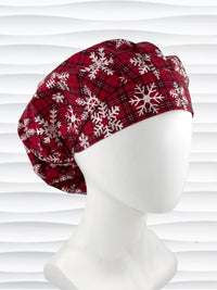 Red plaid bouffant scrub cap by jenscaps with white snowflake patterns displayed on a white mannequin head against a wavy white background.