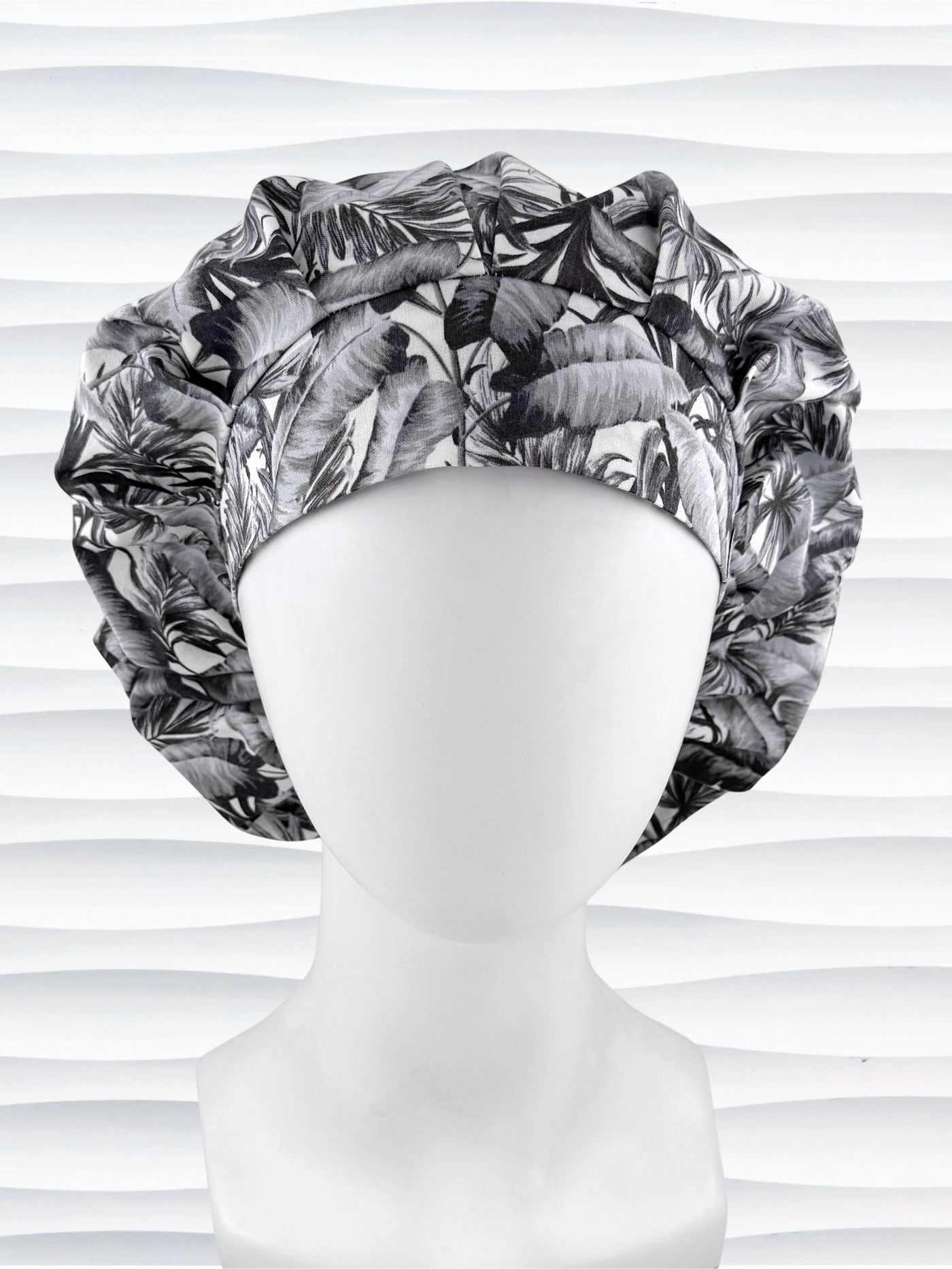 Bouffant style surgical scrub cap by JensCaps with black and white palm trees and displayed on a white mannequin head.