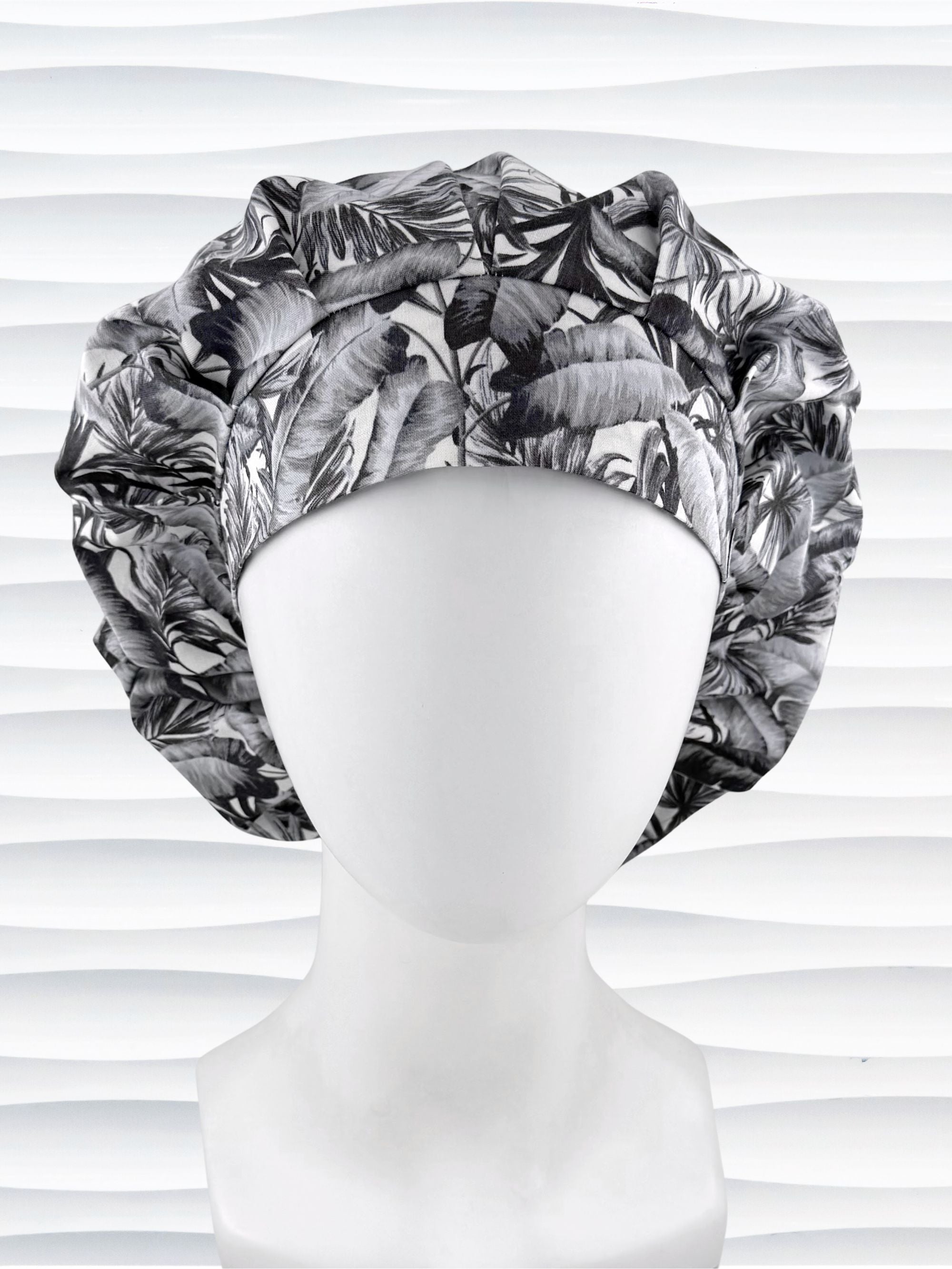 Bouffant style surgical scrub cap by JensCaps with black and white palm trees and displayed on a white mannequin head.