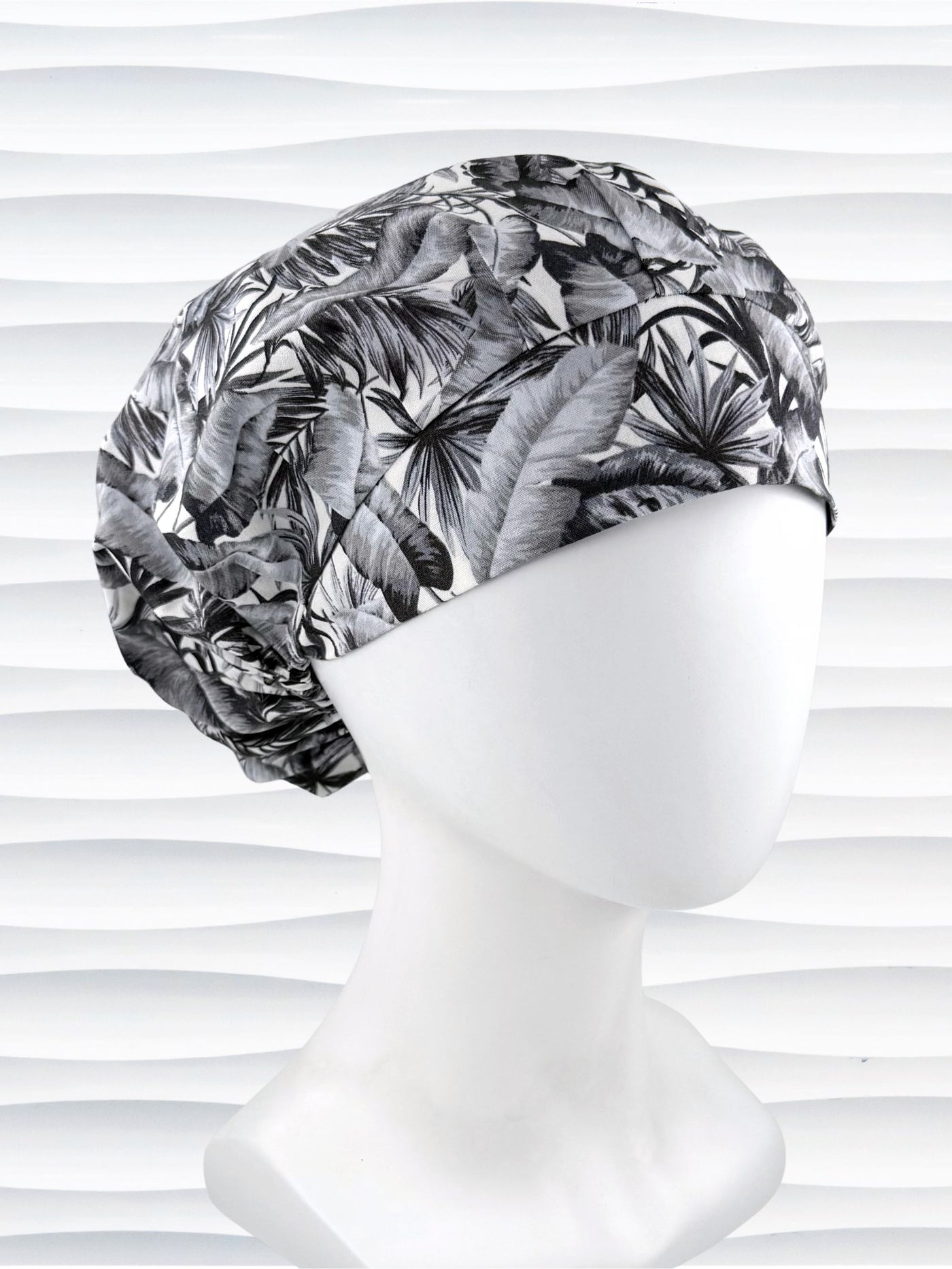 Bouffant style surgical scrub cap by JensCaps with black and white palm trees and displayed on a white mannequin head.