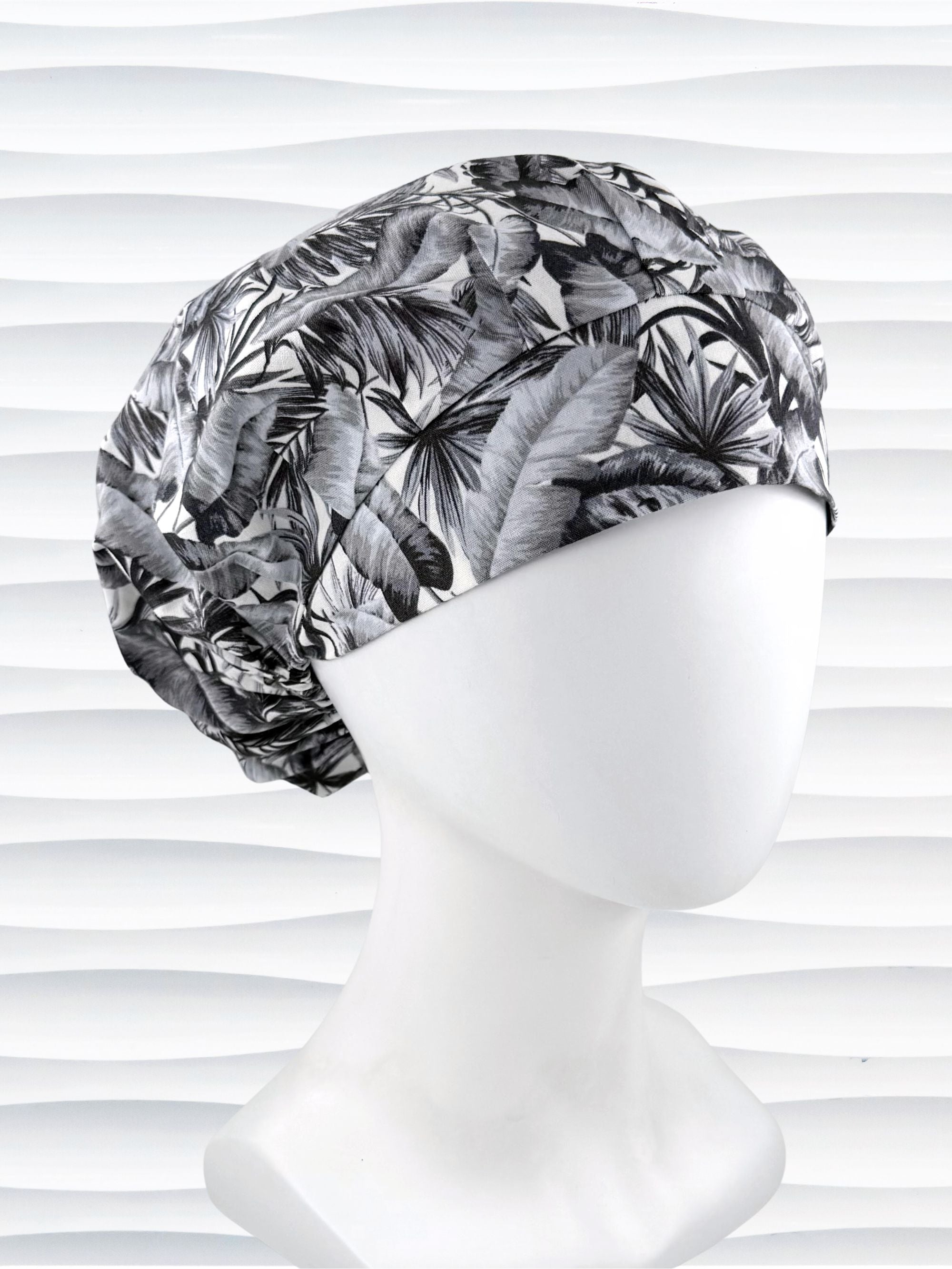 Bouffant style surgical scrub cap by JensCaps with black and white palm trees and displayed on a white mannequin head.