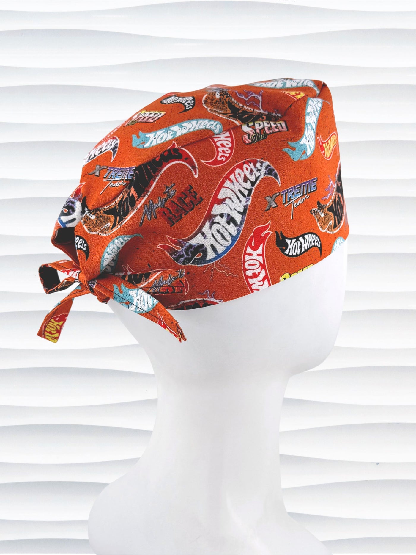Surgeon style surgical scrub cap by JensCaps with dynamic car logos and flame details on an orange background displayed on a white mannequin head