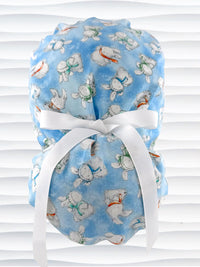 Ponytail style surgical scrub cap by JensCaps with white bunnies wearing beanies and scarves tossed all over this light blue cotton fabric, finished with a ribbon tie, and displayed on a white mannequin head