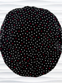 Euro Pixie surgical scrub cap by JensCaps with small red hearts and white dots all over this black cotton fabric and displayed on a white mannequin head.