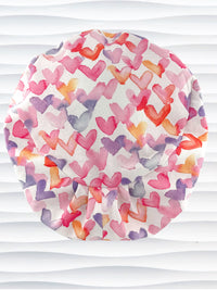 Euro Pixie style surgical scrub cap by JensCaps with watercolor hearts in pastel colors all over white cotton fabric and is displayed on a white mannequin head.