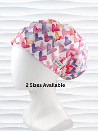 Euro Pixie style surgical scrub cap by JensCaps with watercolor hearts in pastel colors all over white cotton fabric and is displayed on a white mannequin head.