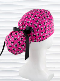 Ponytail style surgical scrub cap by JensCaps with black cats and pink hearts all over this pink background cotton fabric, tied with a ribbon, and displayed on a white mannequin head.