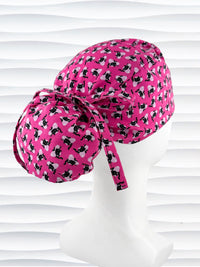 Ponytail style surgical scrub cap by JensCaps with black cats and pink hearts all over this pink background cotton fabric, tied with a ribbon, and displayed on a white mannequin head.
