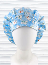 Bouffant style surgical scrub cap by JensCaps with white bunnies wearing beanies and scarves tossed all over this light blue cotton fabric and displayed on a white mannequin head