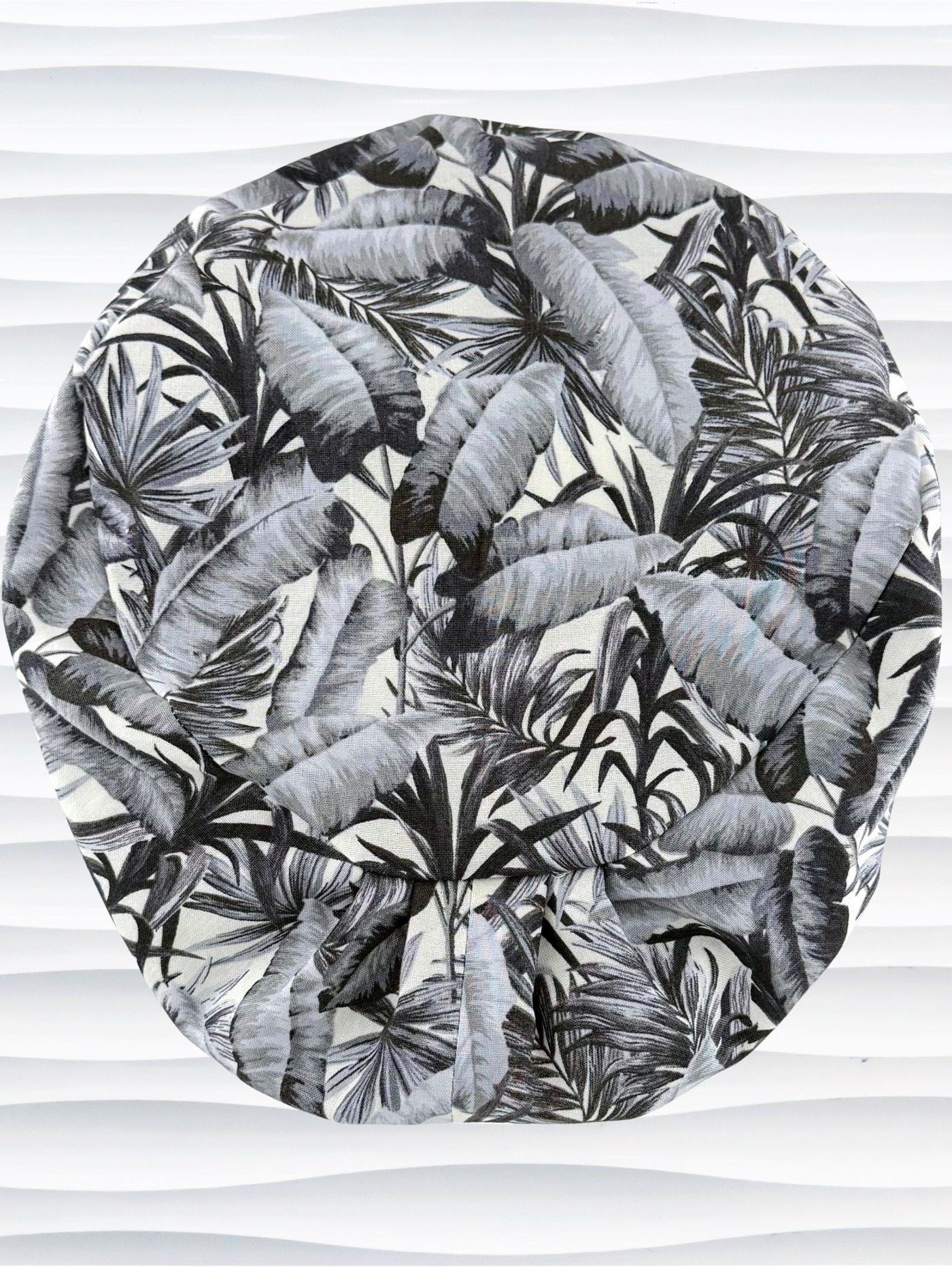 Euro Pixie style surgial scrub cap by JensCaps with black and white palm trees and banana palm leaves displayed on a mannequin head