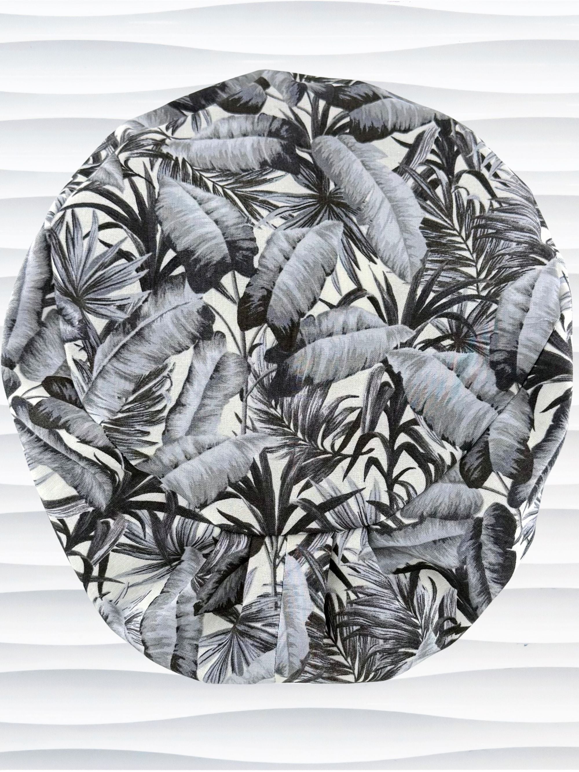 Euro Pixie style surgial scrub cap by JensCaps with black and white palm trees and banana palm leaves displayed on a mannequin head