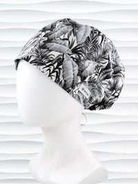 Euro Pixie style surgial scrub cap by JensCaps with black and white palm trees and banana palm leaves displayed on a mannequin head