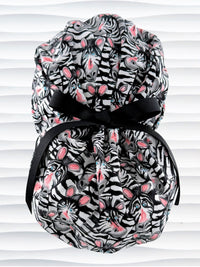 Euro ponytail style surgical scrub cap featuring a black and white zebra print with blue eyes and pink accents with an adjustable back tie and displayed on a mannequin head