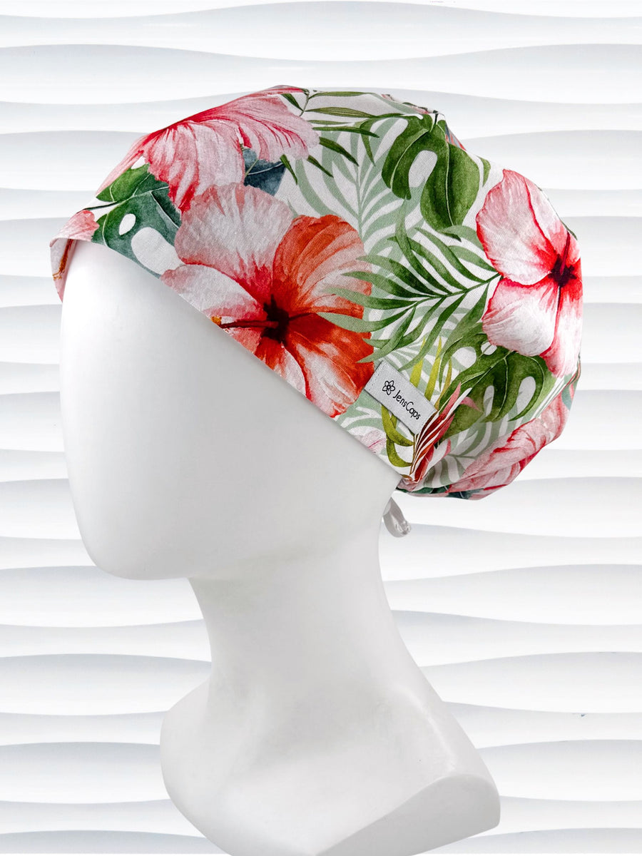 Euro Pixie style surgical scrub cap with red hibiscus flowers and green palm fronds all over white cotton fabric and displayed on a mannequin head.