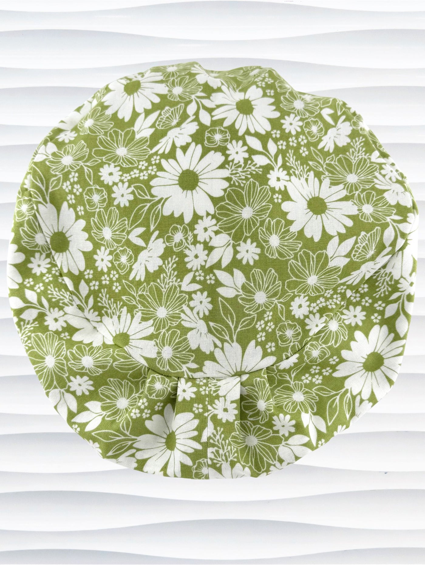 Euro Pixie style surgical scrub cap by JensCaps with white daisies and flowers all over a light green background cotton fabric and displayed on a mannequin head.